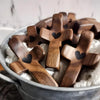 A collection of dark wood comfort prayer crosses with small black hearts floating in white fluffy material.