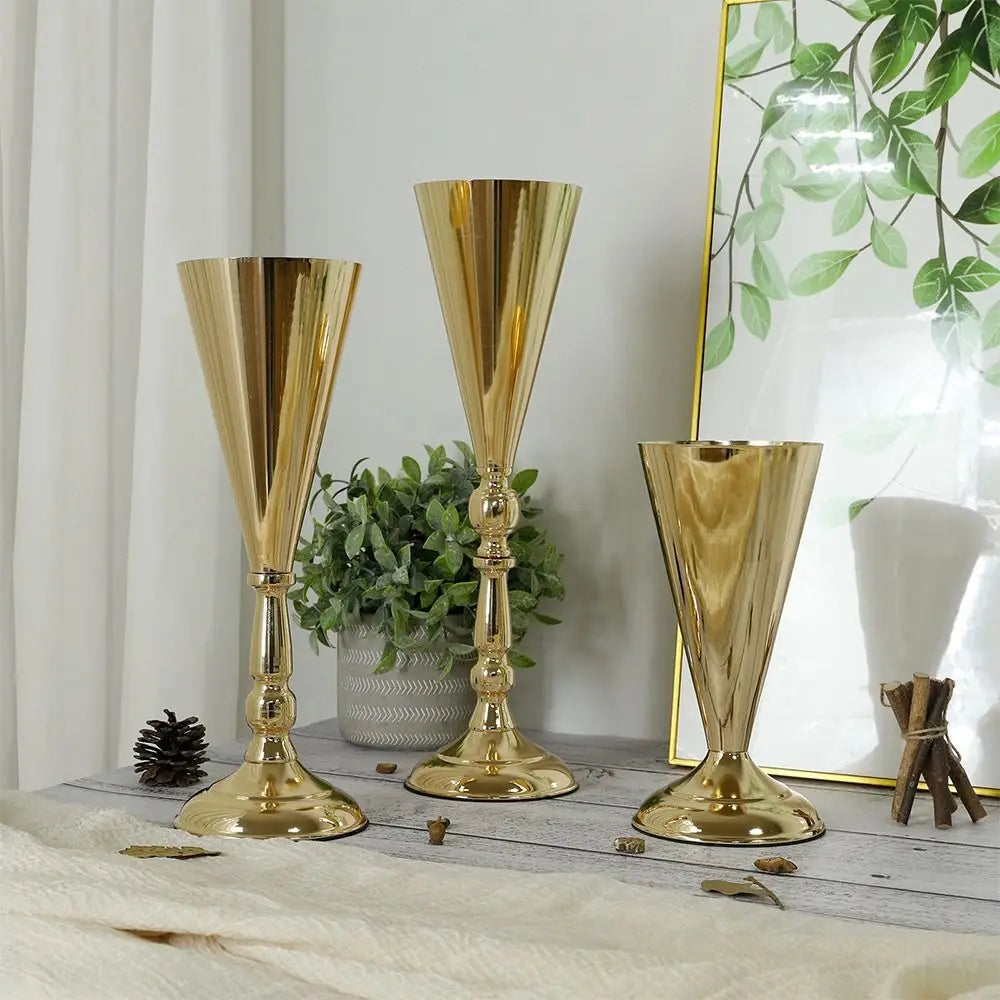 Three elegant golden silver wedding flower vases displayed on a light wooden surface.