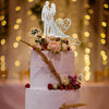 A tiered wedding cake decorated with crystal embellished Mr and Mrs topper and floral accents.