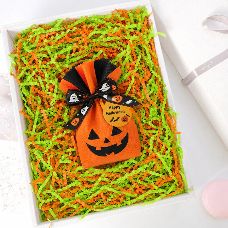 Orange Halloween crinkle paper shred filler for treat bags and décor with a pumpkin-shaped tag