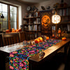 A vibrant floral linen table runner with skulls and pumpkins displayed on a wooden table.