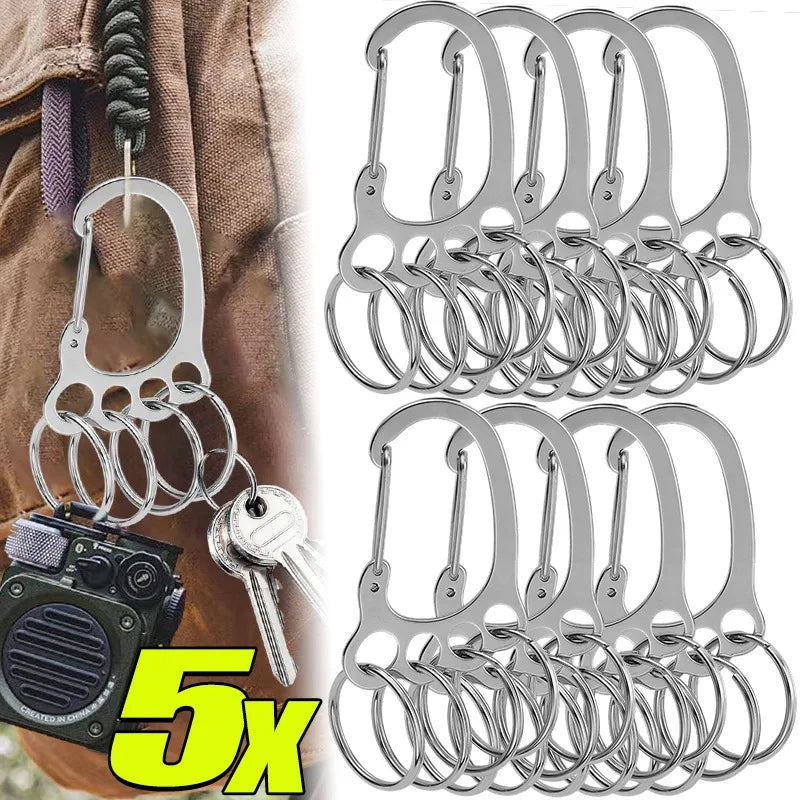 A set of five stainless steel keychains with multi-loop designs displayed next to a camera.