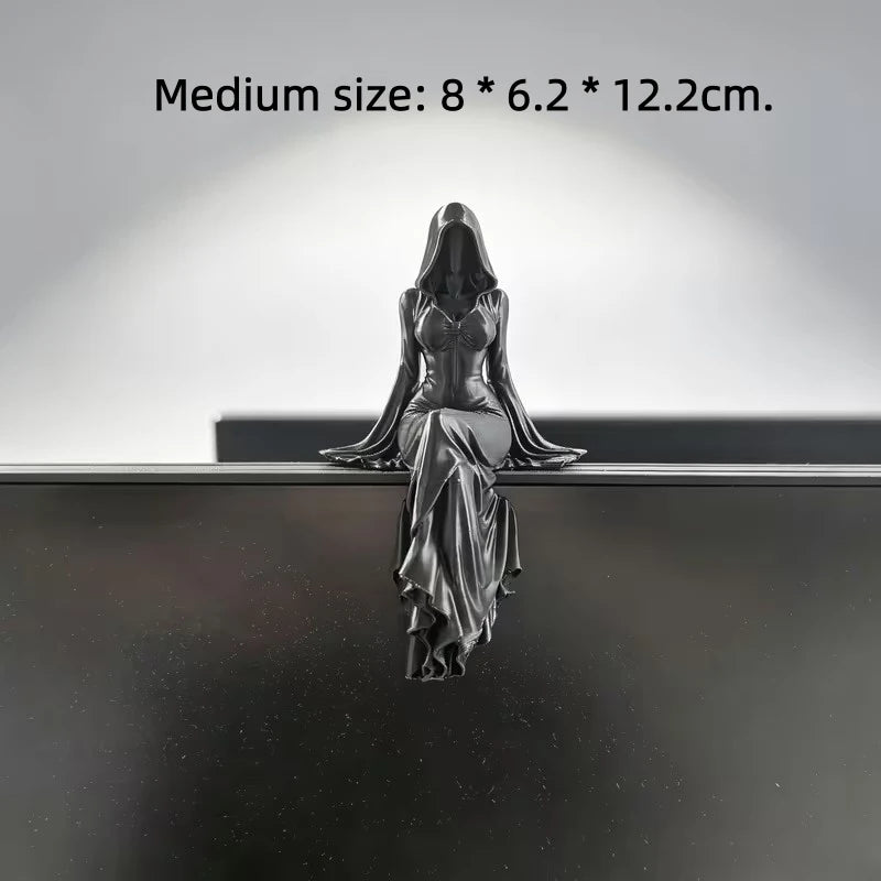 A silver-toned desktop figurine of a female figure in a flowing gown, displayed against a dark background.