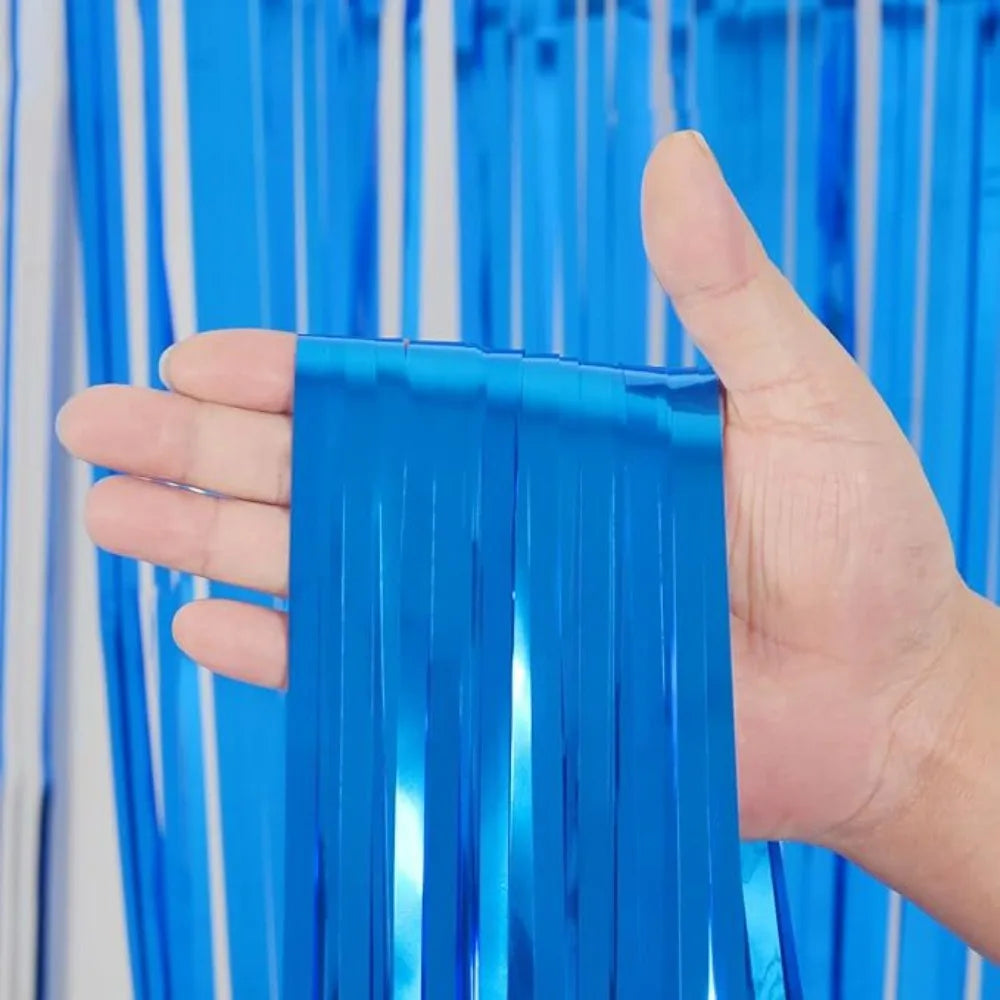 Une main tient une bande verticale de rideaux à franges métalliques arc-en-ciel bleu vif.