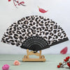 A leopard print folding hand fan with a black handle displayed against a light background.