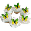 A collection of green and yellow butterfly shaped frosting cupcake toppers arranged in a circle.