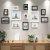 A collection of various sized wooden picture frames displayed on a light gray wall.