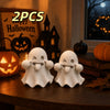 Two white kawaii ghost statues for Halloween decor displayed on a wooden surface.