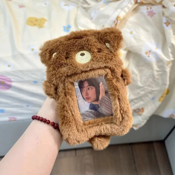 A brown fluffy plush photocard holder with a clear window displaying a picture of a person.