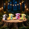 A set of colorful resin bear figurines in white, yellow, pink, and green displayed on a wooden log in a forest setting.