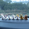 A row of eight small dog figurines, each wearing a beaded collar, lined up on a gray surface.