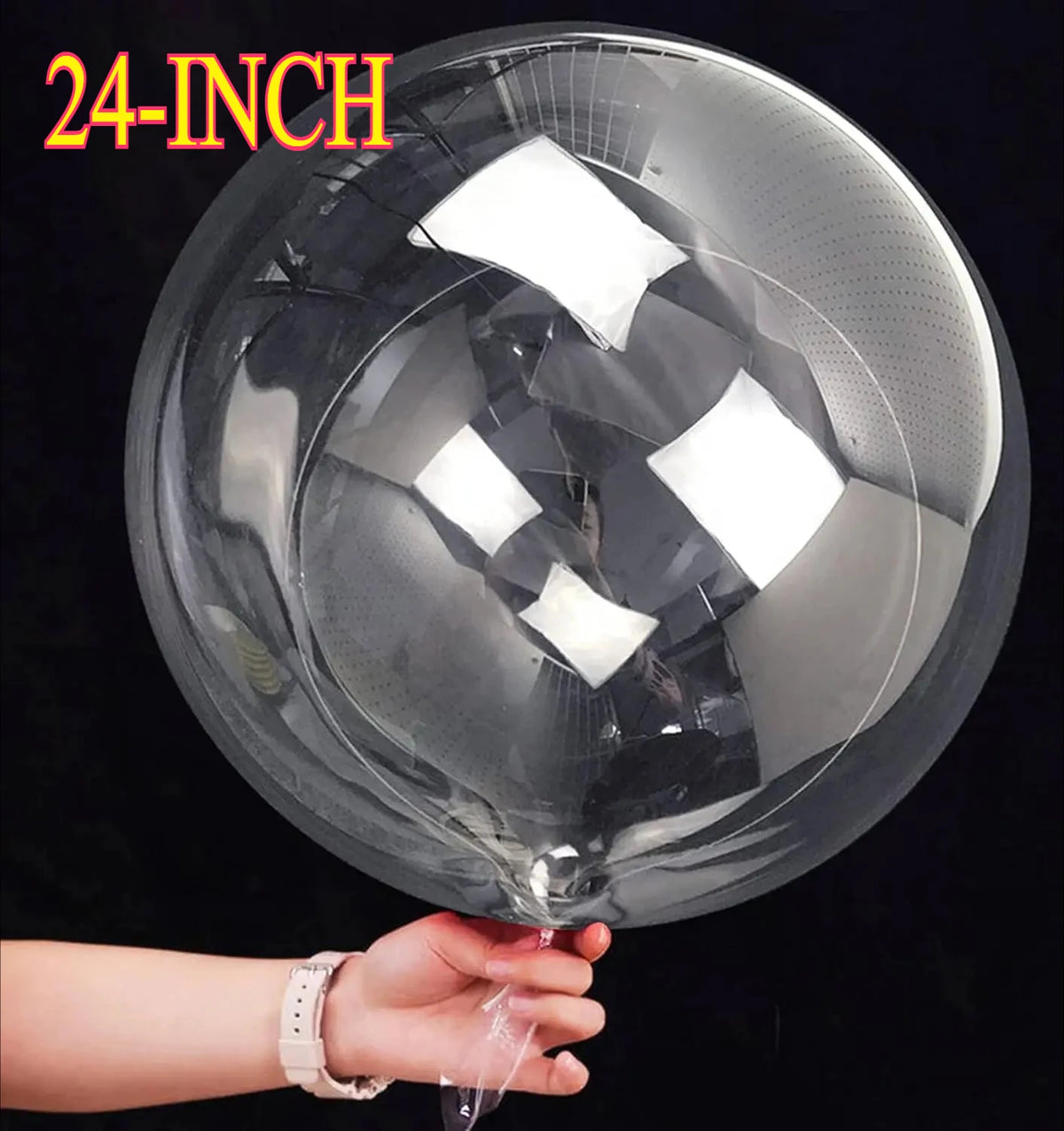 A hand holds a large 24-inch clear bubble balloon, showing its reflective surface and spherical shape.