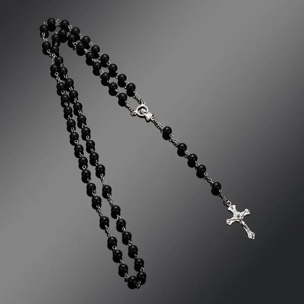 A black beaded rosary necklace featuring a vintage cross and Virgin Mary pendant.