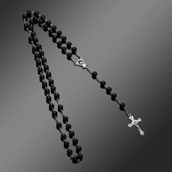 A black beaded rosary necklace featuring a vintage cross and Virgin Mary pendant.