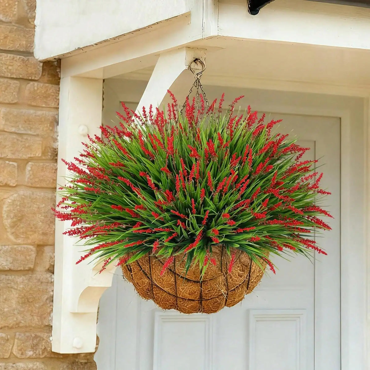 A vibrant artificial lavender plastic wreath with bright red spikes hangs on a white door frame.