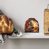 A cute mouse figurine wearing a chef hat is displayed in a hollowed-out log on a white shelf.