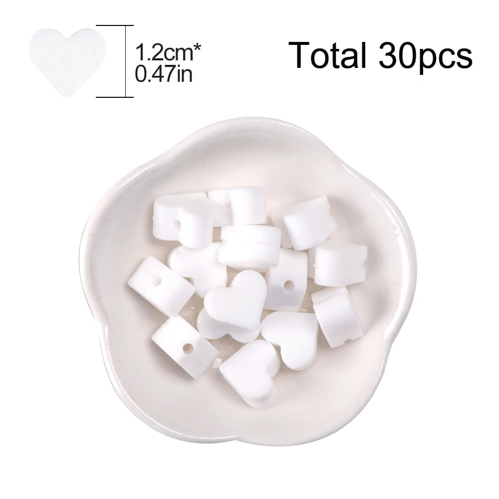 A white silicone heart bead set containing 30 pieces displayed in a small dish.