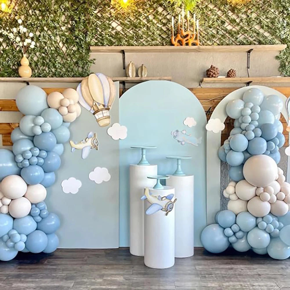 A display of pastel blue and white latex balloons arranged in clusters and columns against a green wall backdrop.