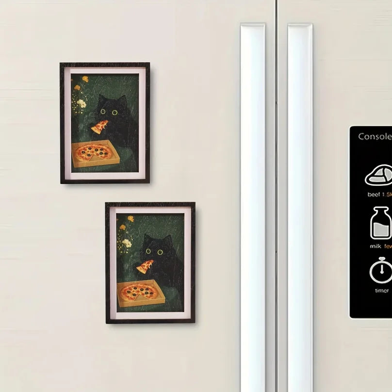 A framed print featuring a black cat looking at a slice of pizza, displayed on a light-colored wall.