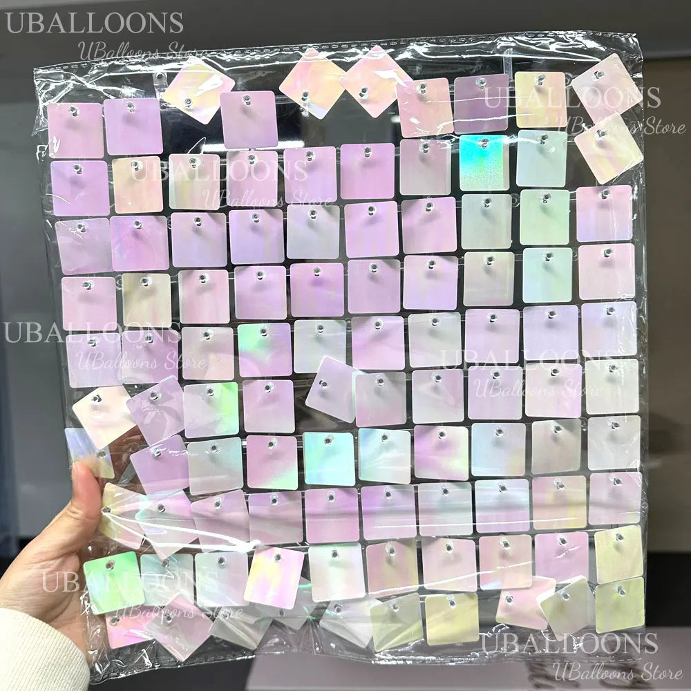 A clear plastic bag filled with square pink and iridescent shimmer sequins used as wall backdrop panels for party decor.