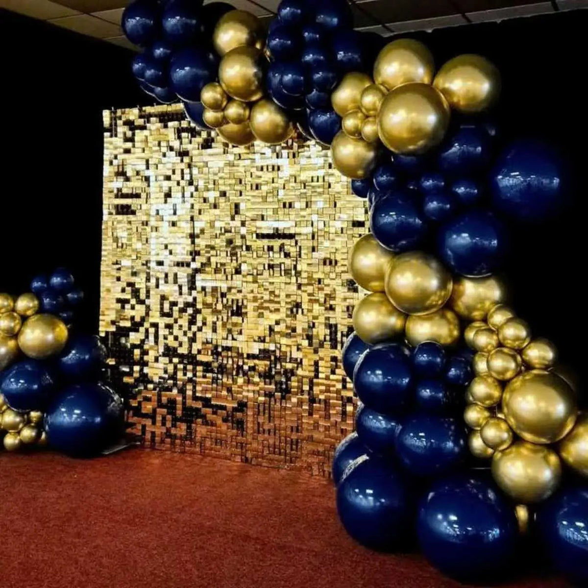 A balloon arch display featuring gold and navy blue balloons against a textured gold background.