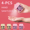 Four pieces of pink hand sanitizer spray bottles are shown being held in a hand against a pink background.