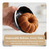 A hand holds a dark nonstick mini fluted cake pan filled with baked cake.