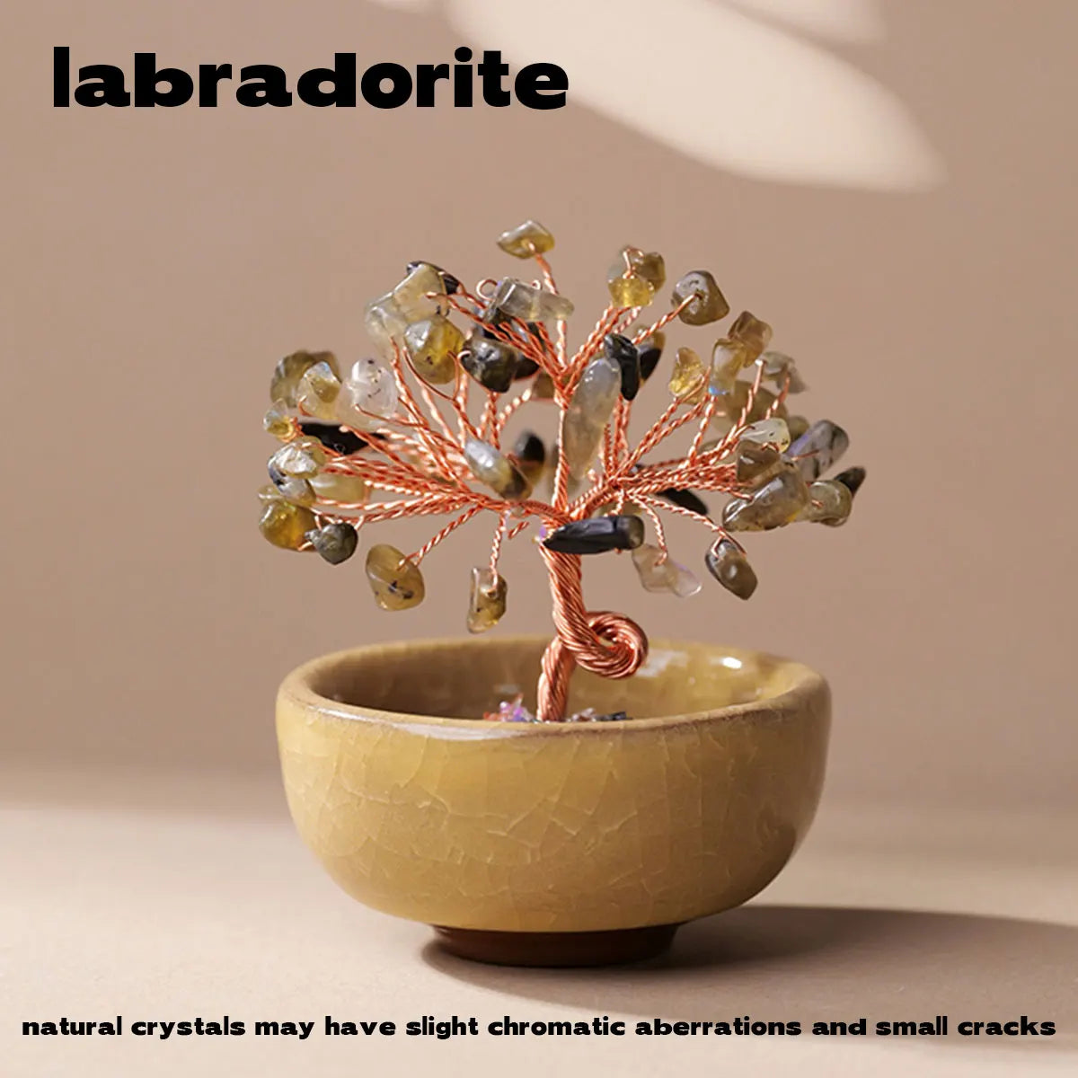 A handcrafted crystal tree with natural stones mounted on a copper wire base sits in a light yellow bowl.