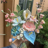 A handmade crochet flower bouquet featuring various shades of pink, blue, and white flowers.