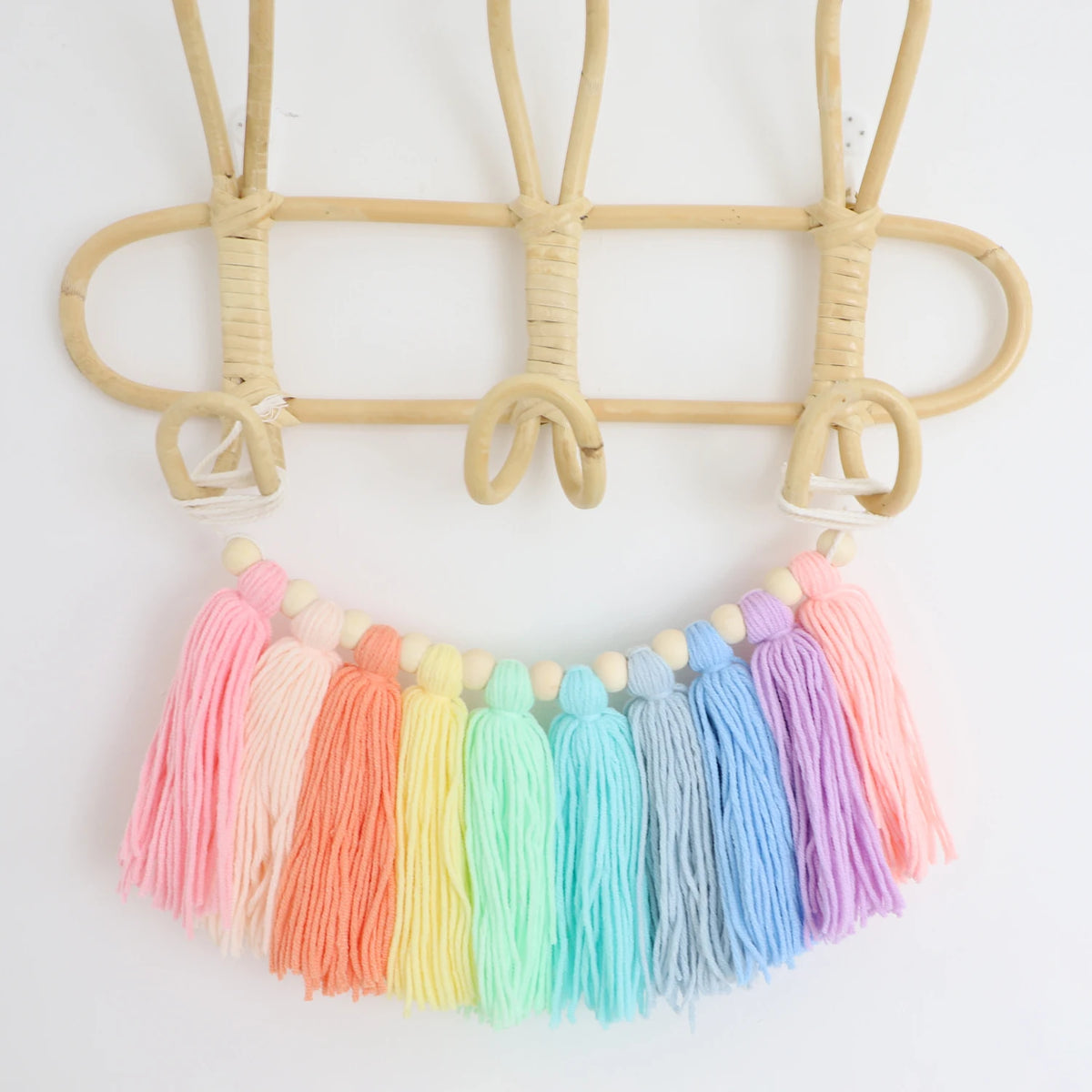Handmade boho rainbow tassel garland featuring wooden beads and natural fiber stringing.