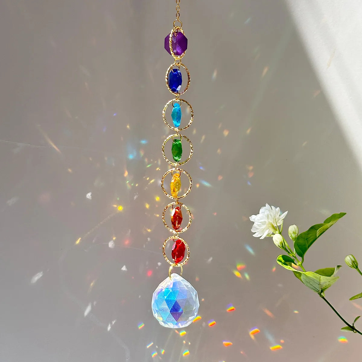 A delicate gold necklace featuring a string of colorful crystal prisms and rainbow reflections.