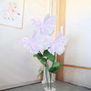 White silk artificial butterfly decoration with green leaves displayed against a light wall.