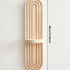 A vertical wooden wall shelf with an arched design featuring parallel grooves and a circular cutout.