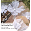Three large white mesh flowers used as wedding decoration in an outdoor setting.