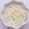 A white dish filled with small, white and yellow 3D resin flower gems for crafts
