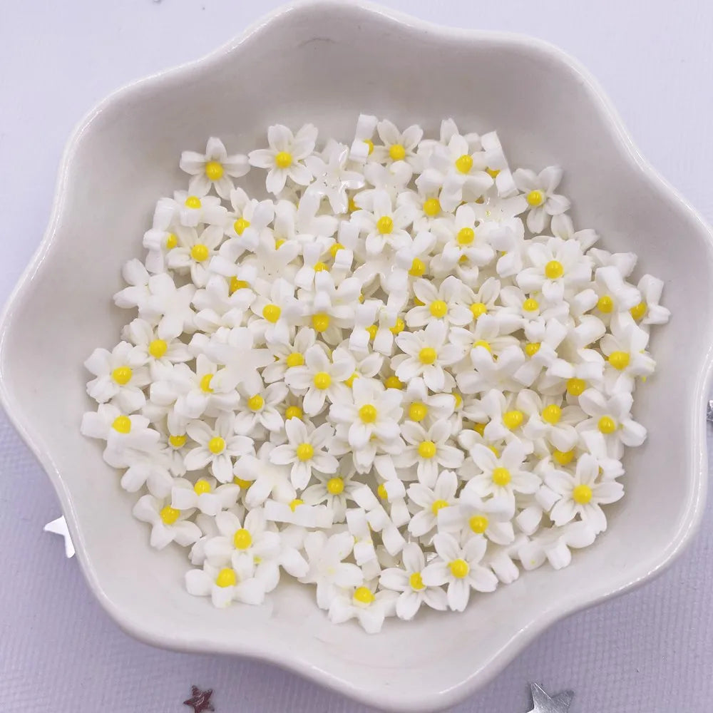 A white dish filled with small, white and yellow 3D resin flower gems for crafts