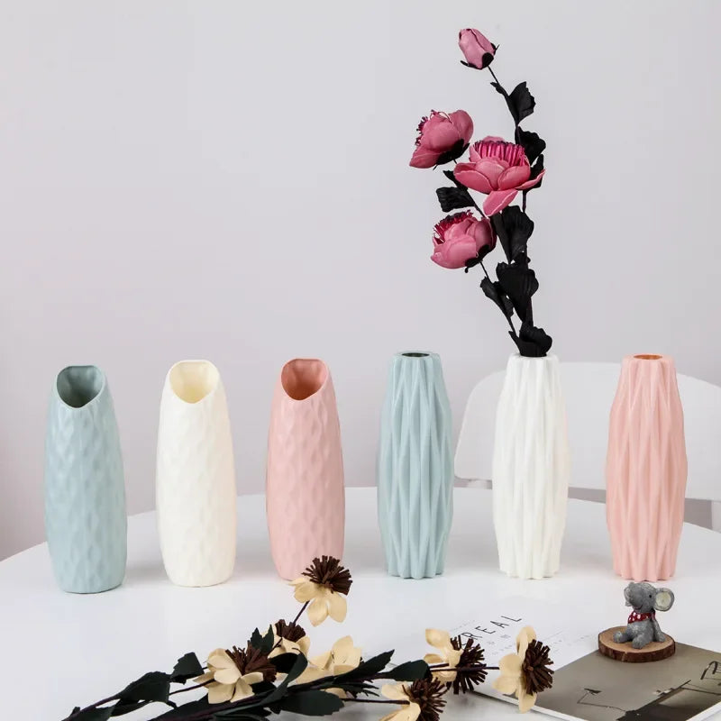 A collection of white and pink Nordic style decorative plastic vases for flowers displayed on a white surface.