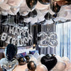 A display of black and white balloons and a silver banner decorating a party setup.
