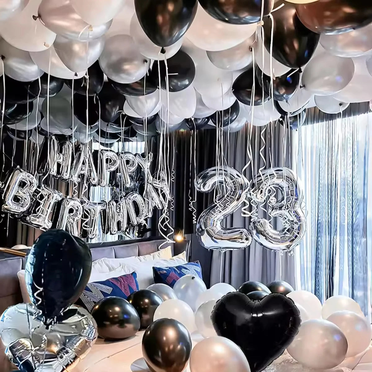 A display of black and white balloons and a silver banner decorating a party setup.