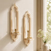 A rustic wooden wall shelf with an arched design holds a lit candle and is mounted on a light-colored wall.