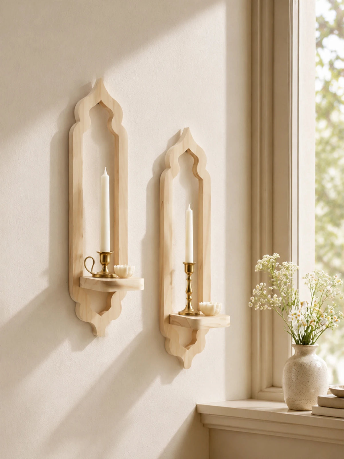 A rustic wooden wall shelf with an arched design holds a lit candle and is mounted on a light-colored wall.