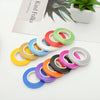 A collection of colorful satin balloon ribbon rolls arranged diagonally on a white surface.