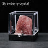 A pink strawberry crystal rough stone specimen displayed inside a clear glass box.