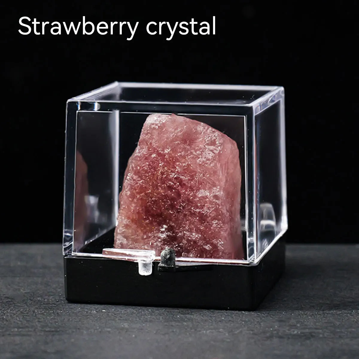A pink strawberry crystal rough stone specimen displayed inside a clear glass box.