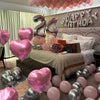 A display of pink and silver balloons decorating a birthday setup with a wall sign.