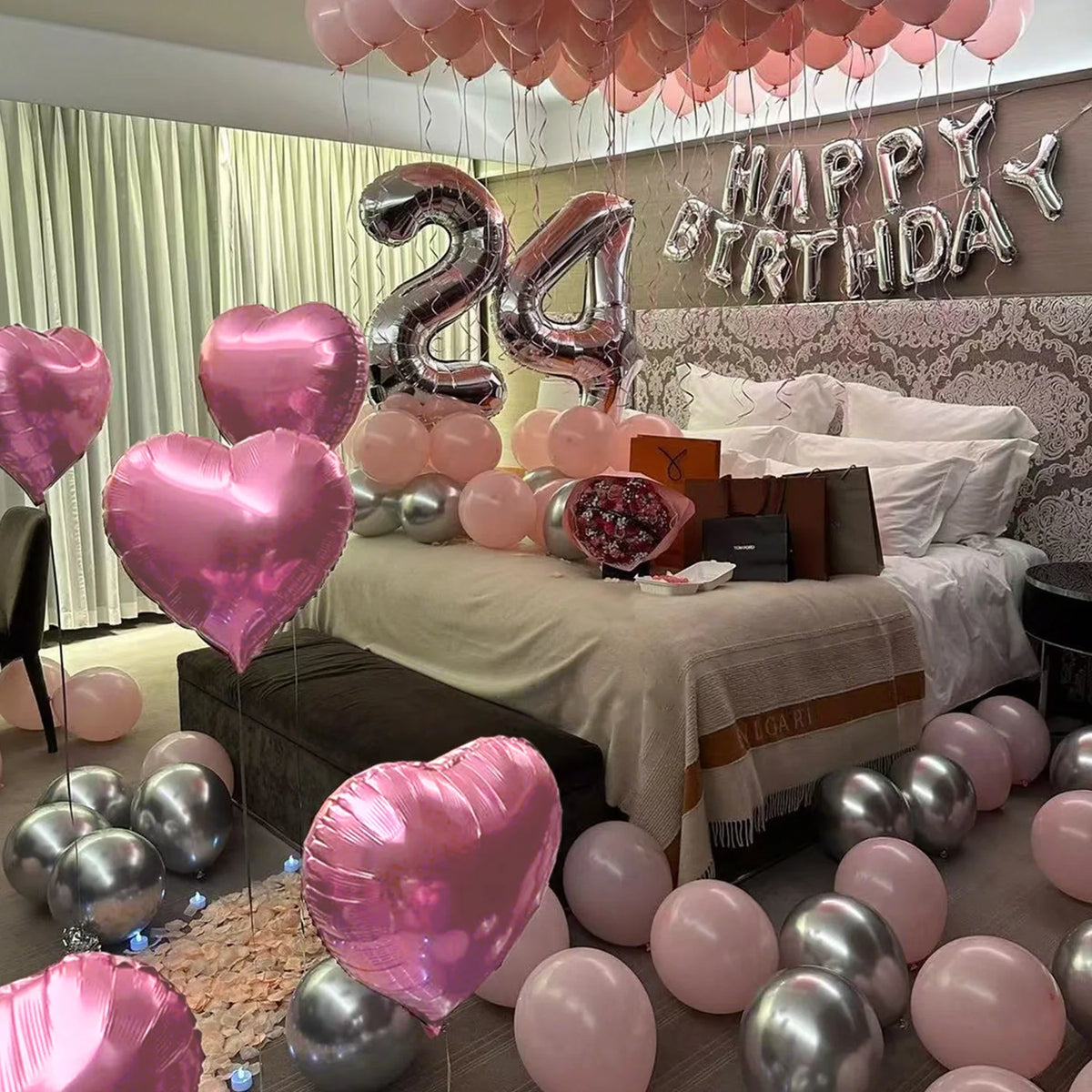 A display of pink and silver balloons decorating a birthday setup with a wall sign.