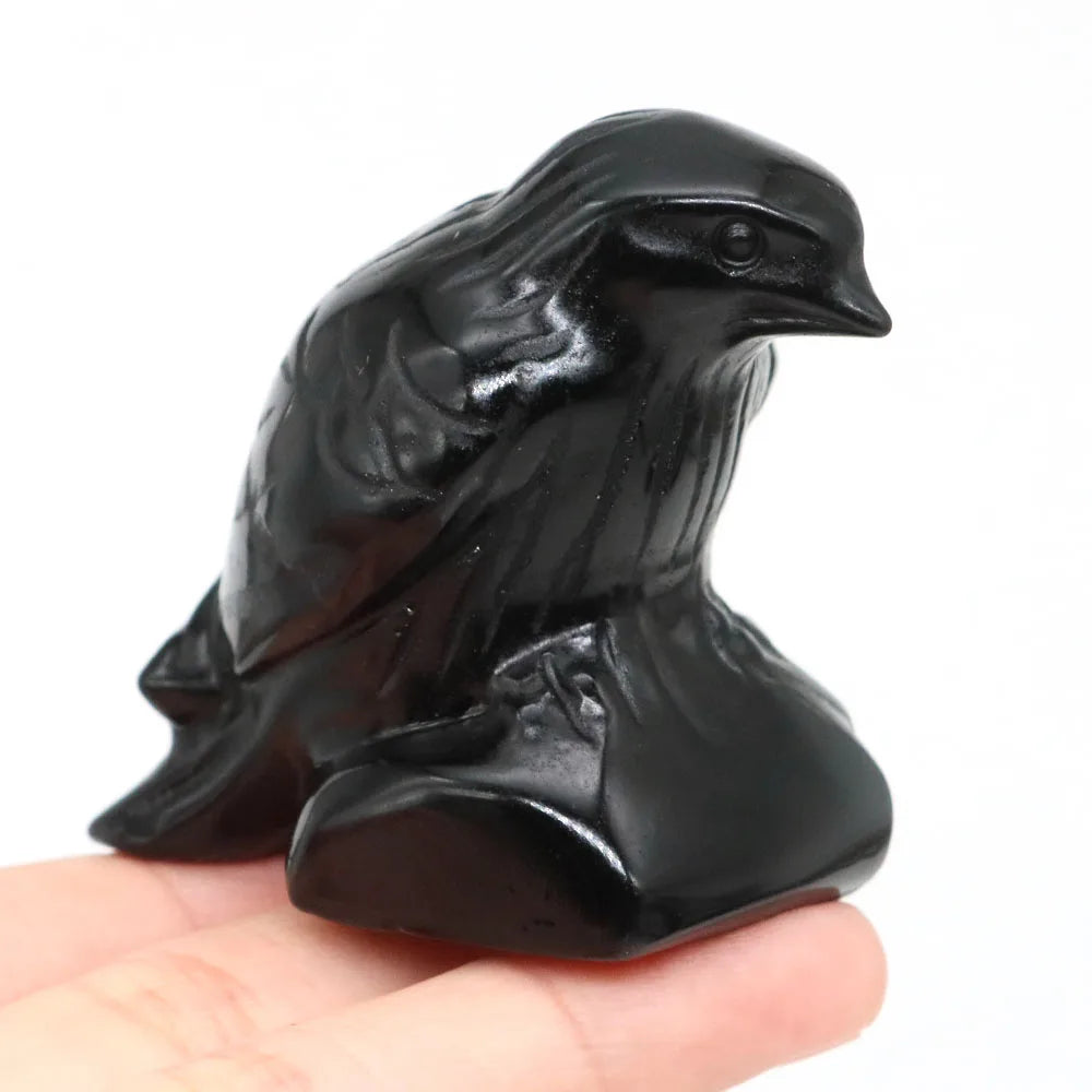 Hand-carved black obsidian raven figurine resting on a hand