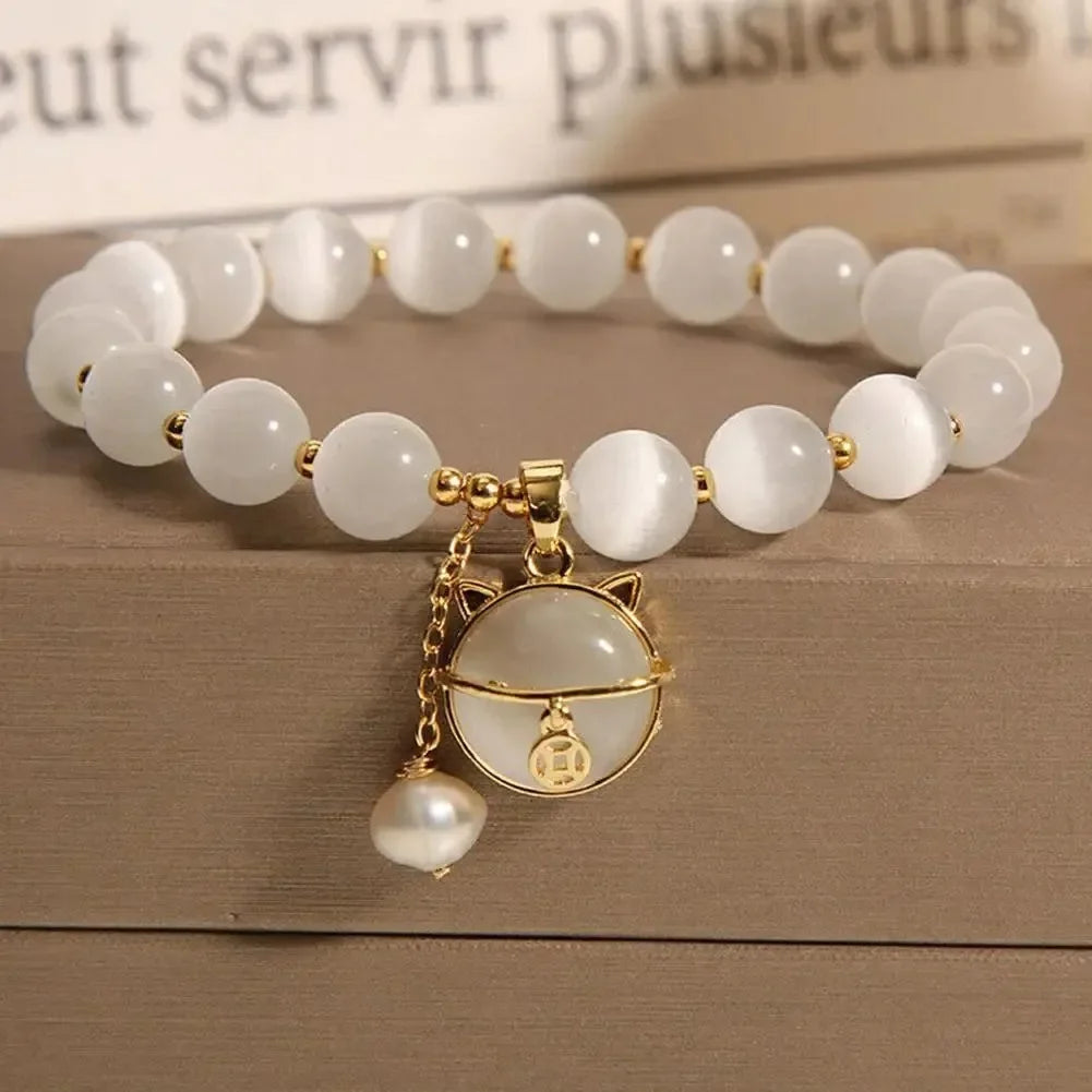 A white natural stone lily of the valley bracelet with gold accents displayed on a wooden surface.