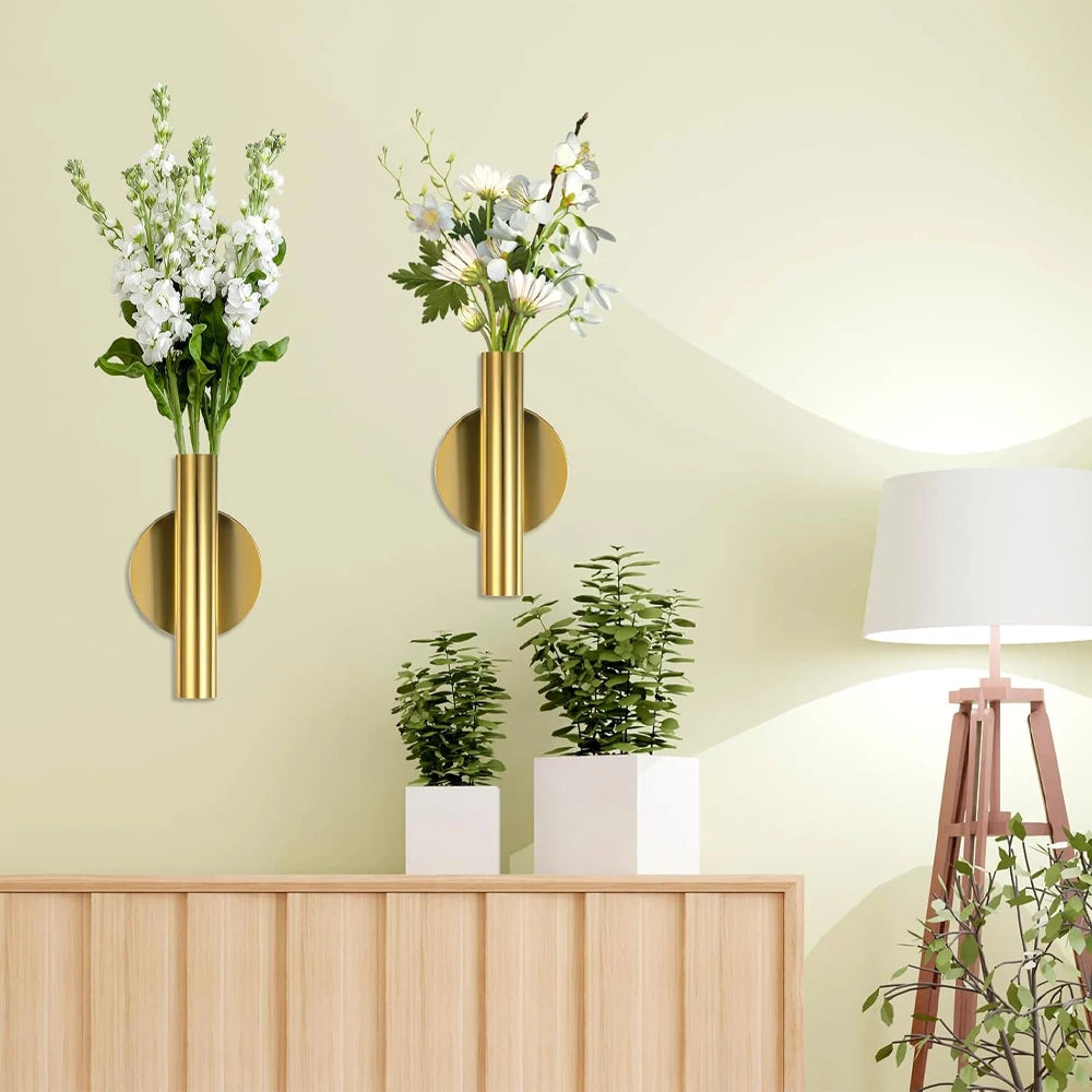 Minimalist wall-mounted metal flower vase with white flowers displayed on a light green wall.