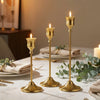 A set of three gold vintage European style metal candle holders displayed on a white marble surface.